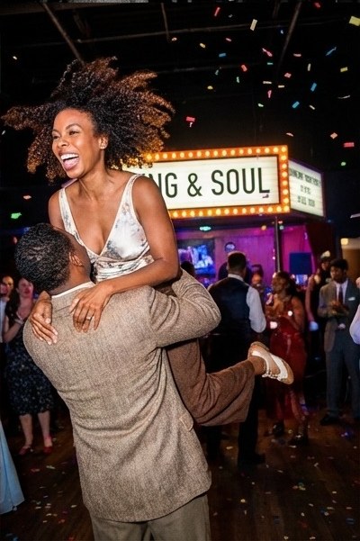 Dancer lifted in celebration under a marquee at a real event